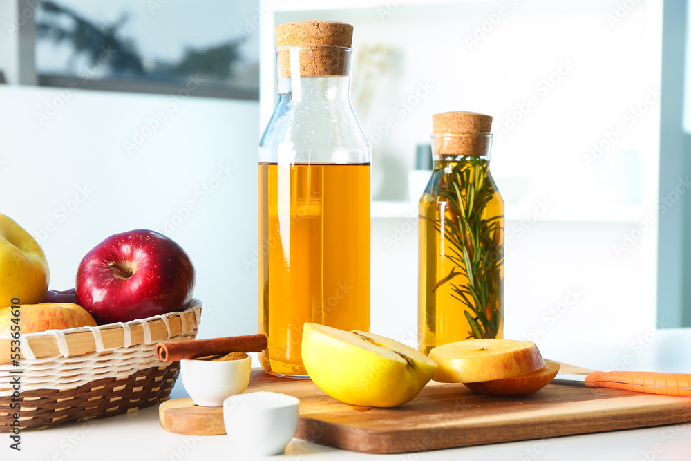 Wooden board with bottles of fresh apple juice and fruits on table in kitchen