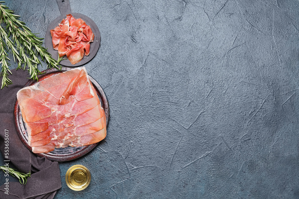 Composition with slices of tasty ham, olive oil and rosemary on dark background