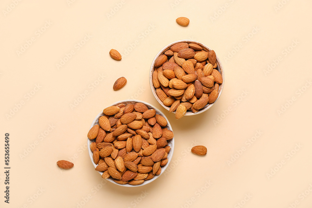 Bowls of almonds on beige background