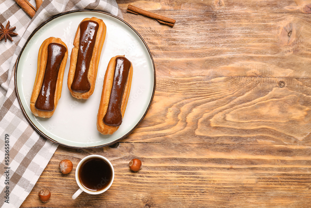 Plate with tasty chocolate eclairs and cup of coffee on wooden table