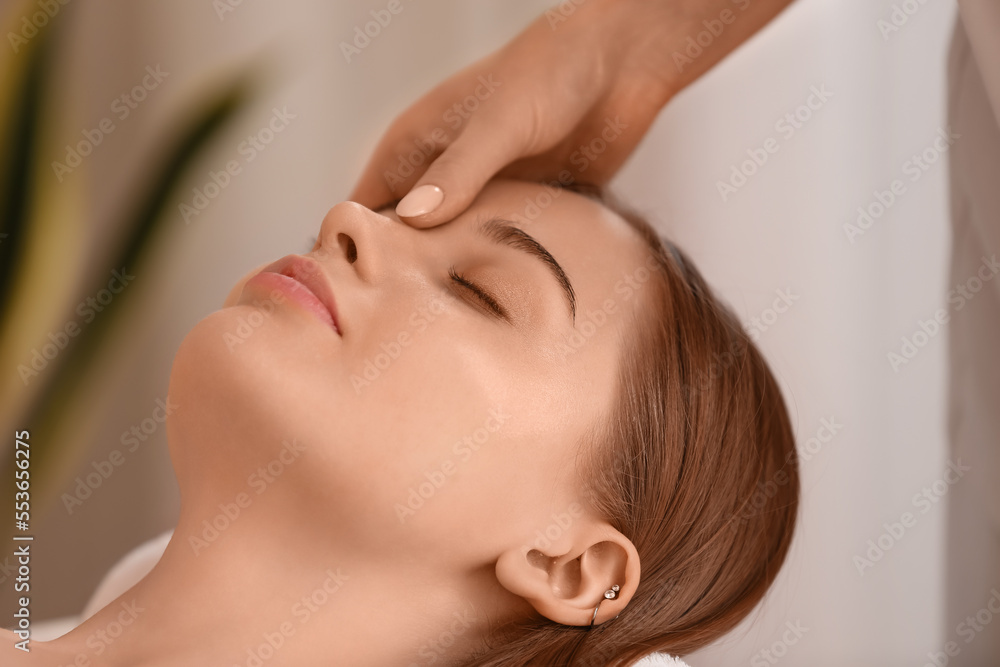 Pretty young woman receiving face massage in beauty salon