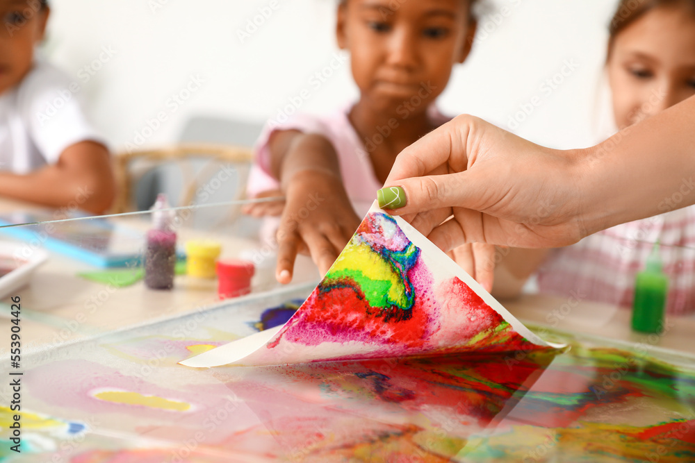 Female teacher marbling paper in workshop for Ebru painting, closeup