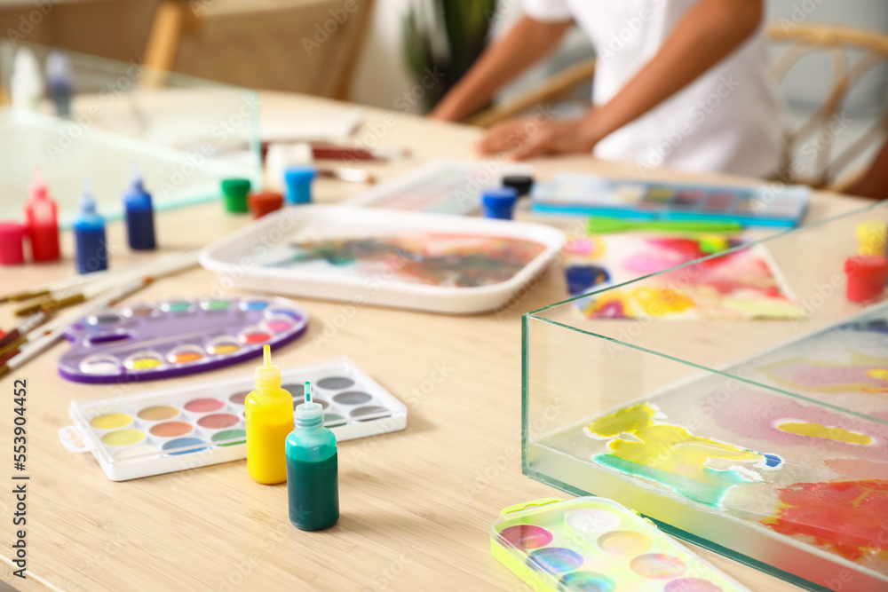 Container with water and paints for Ebru on table in workshop, closeup