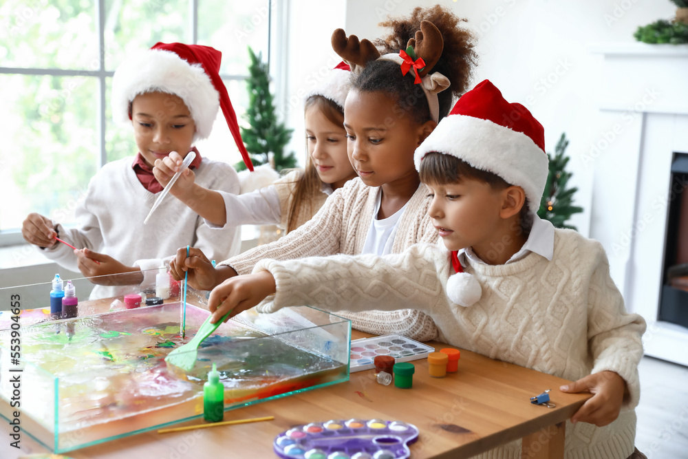 Little children in Santa hats painting on water at workshop. Ebru art