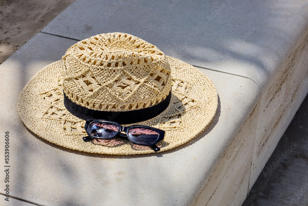 Beautiful hat with sunglasses on fence in park, closeup