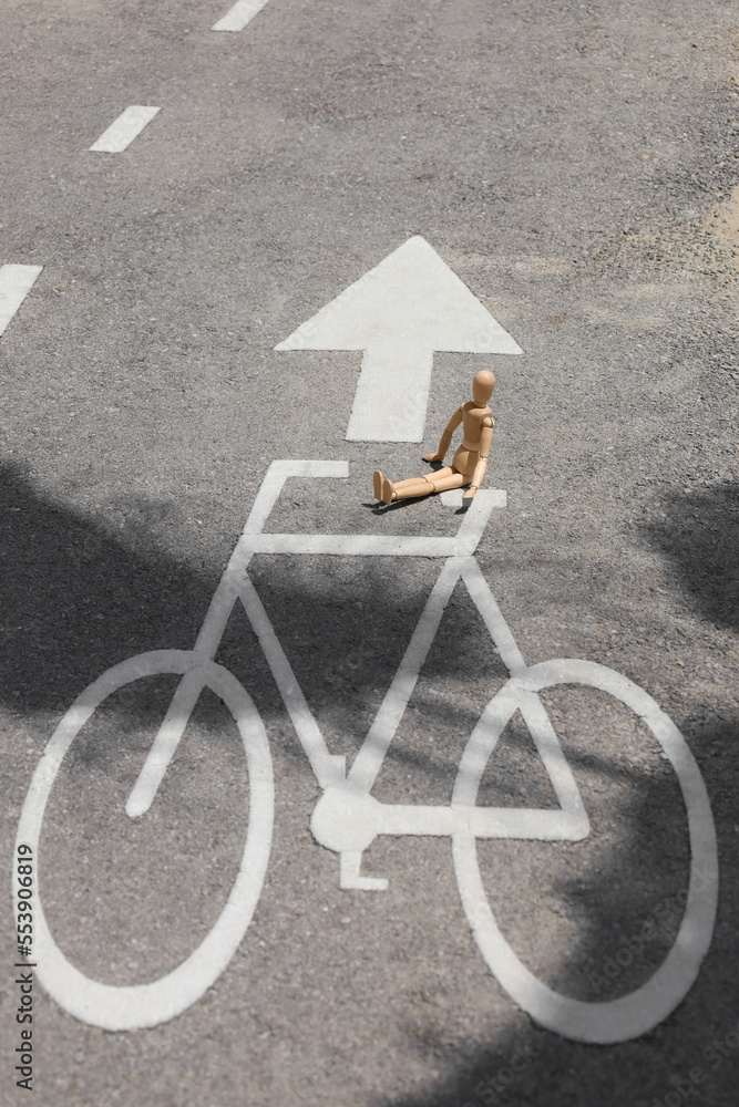 Wooden mannequin on road with bicycle signs in city