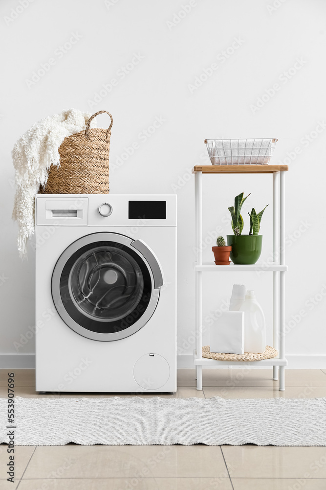 Interior of laundry room with washing machine, shelving unit and houseplants