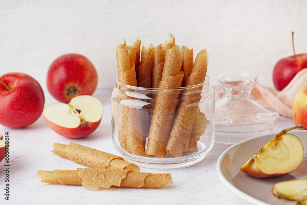 Glass jar with tasty apple pastilles on light background