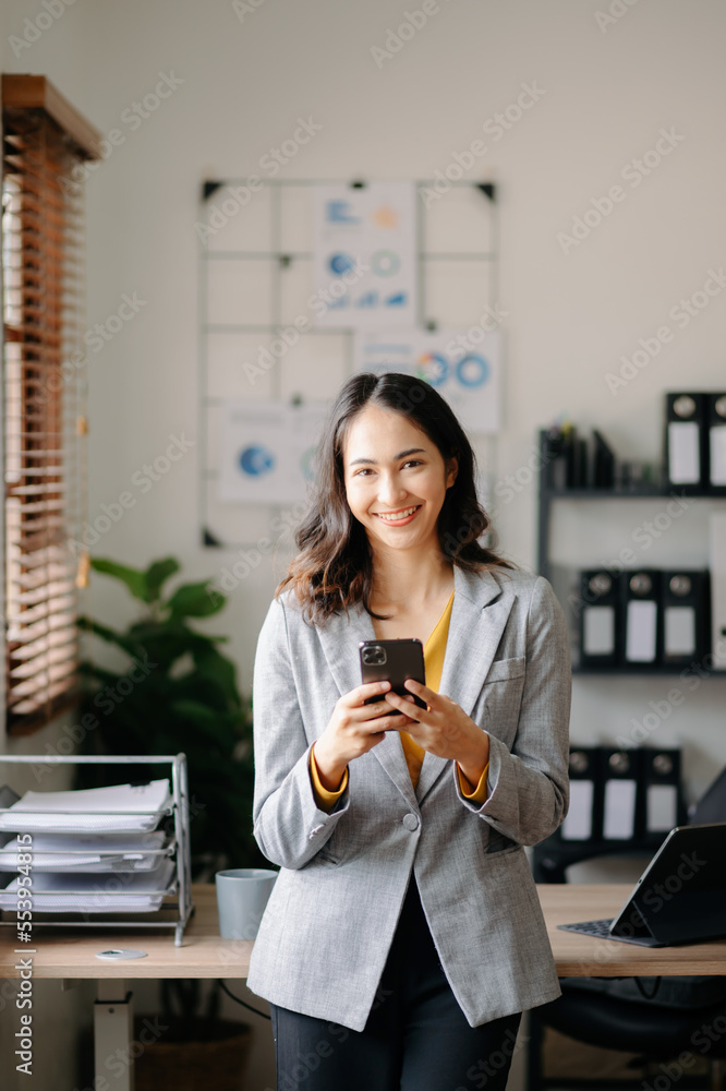 Young attractive Asian female office worker business suits smiling at camera in office .