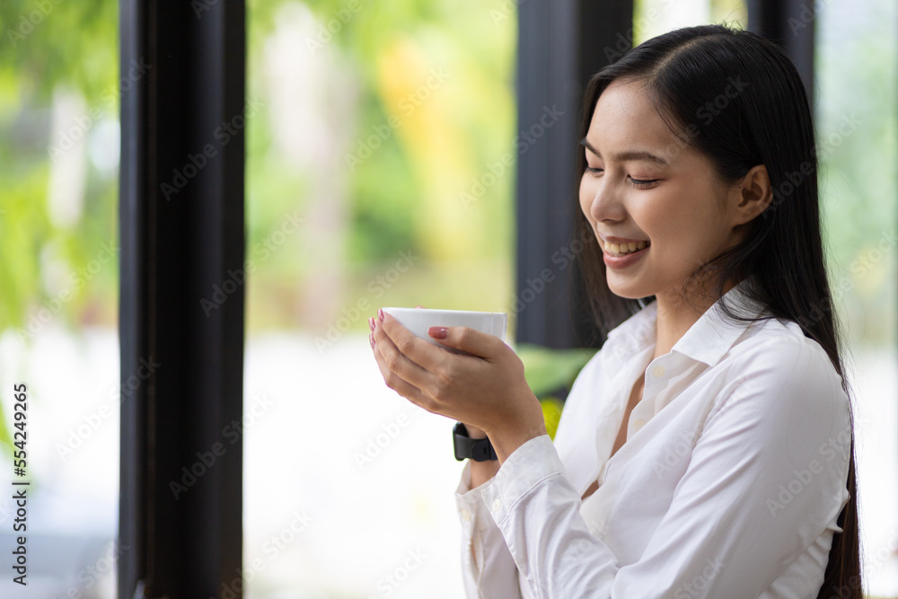 快乐的亚洲女人早上喝咖啡。