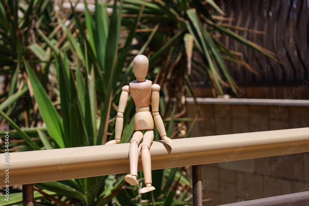 Wooden mannequin on railing in park, closeup