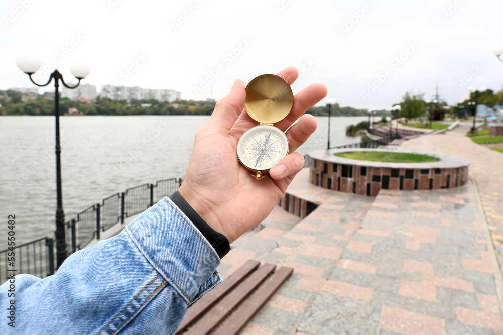 公园里拿着金色指南针的男人，特写