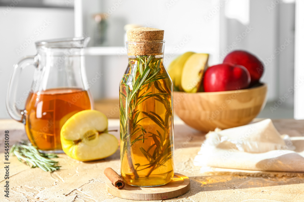 Bottle of fresh apple juice with rosemary on table