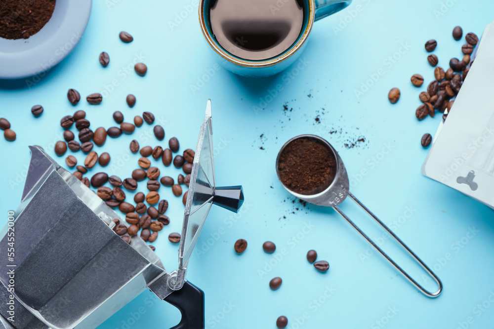 Composition with geyser coffee maker and beans on blue background