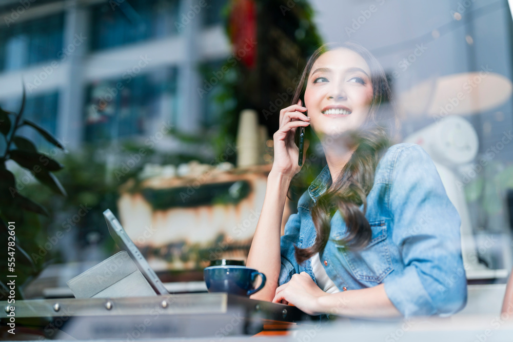 casual smart asian female entrepreneur small business working at coworking space hand using smartpho