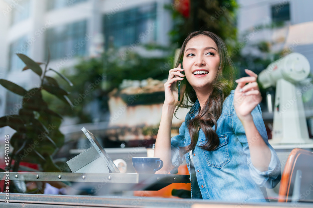 casual smart asian female entrepreneur small business working at coworking space hand using smartpho