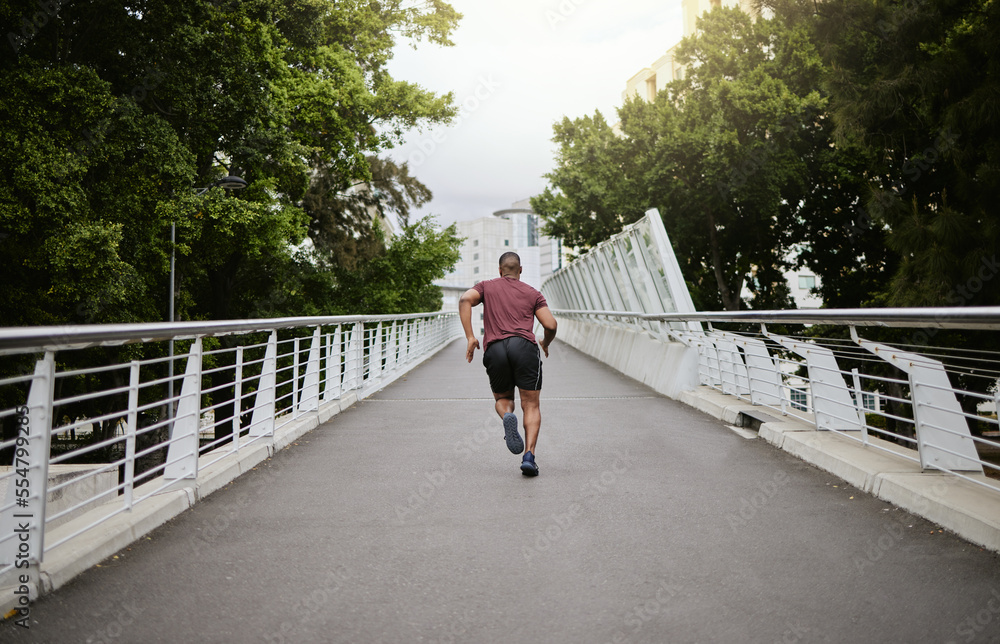 Fitness, man and running in the city park for healthy exercise, cardio workout or training in the ou