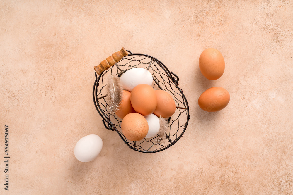 Eggs in metallic basket on beige background. Top view of raw brown eggs and white eggs with copy spa