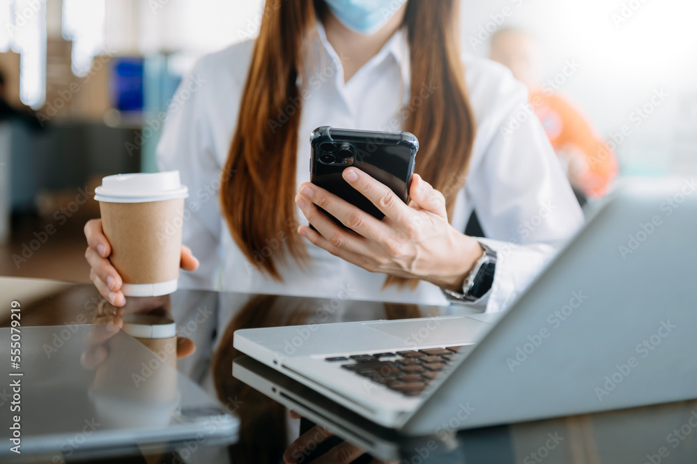  businesswoman typing laptop computer and digital tablet while holding coffee