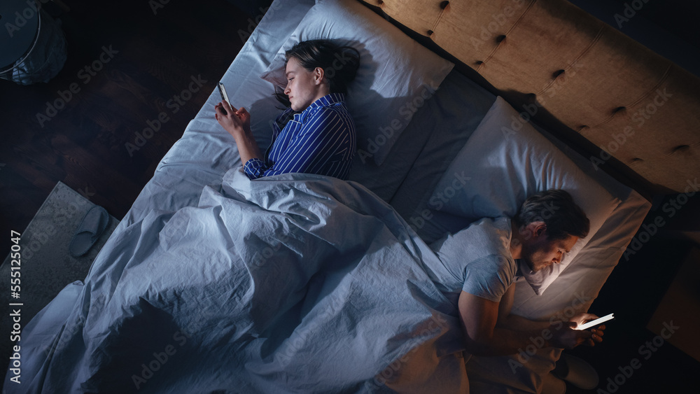 Top View Apartment Bedroom: Caucasian Couple Lying in Bed, Both Using Smartphones. Family of Two Usi