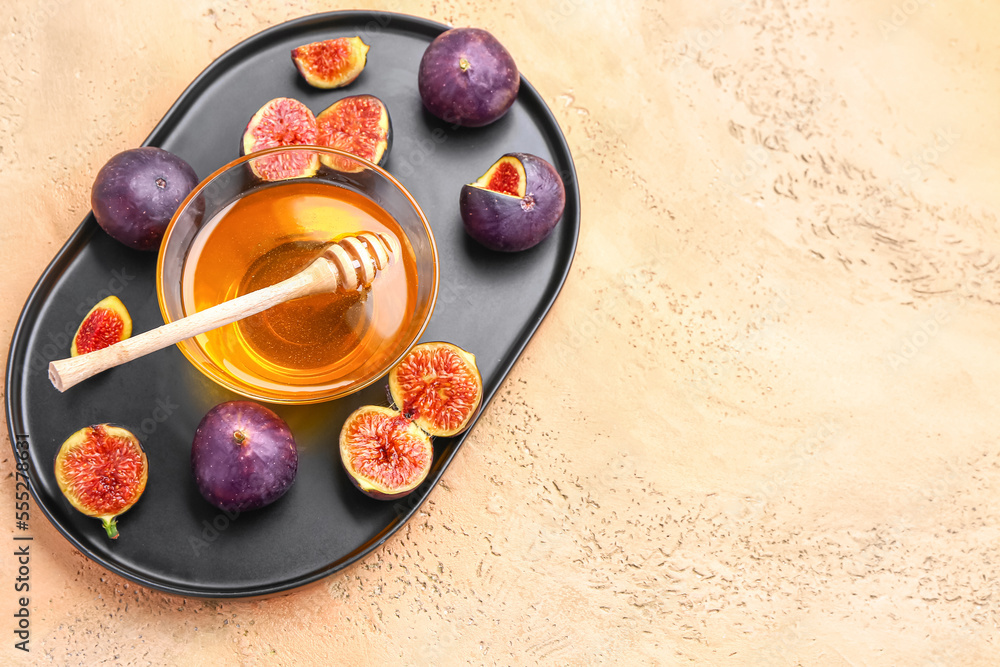 Plate with fresh figs and bowl of honey on color background