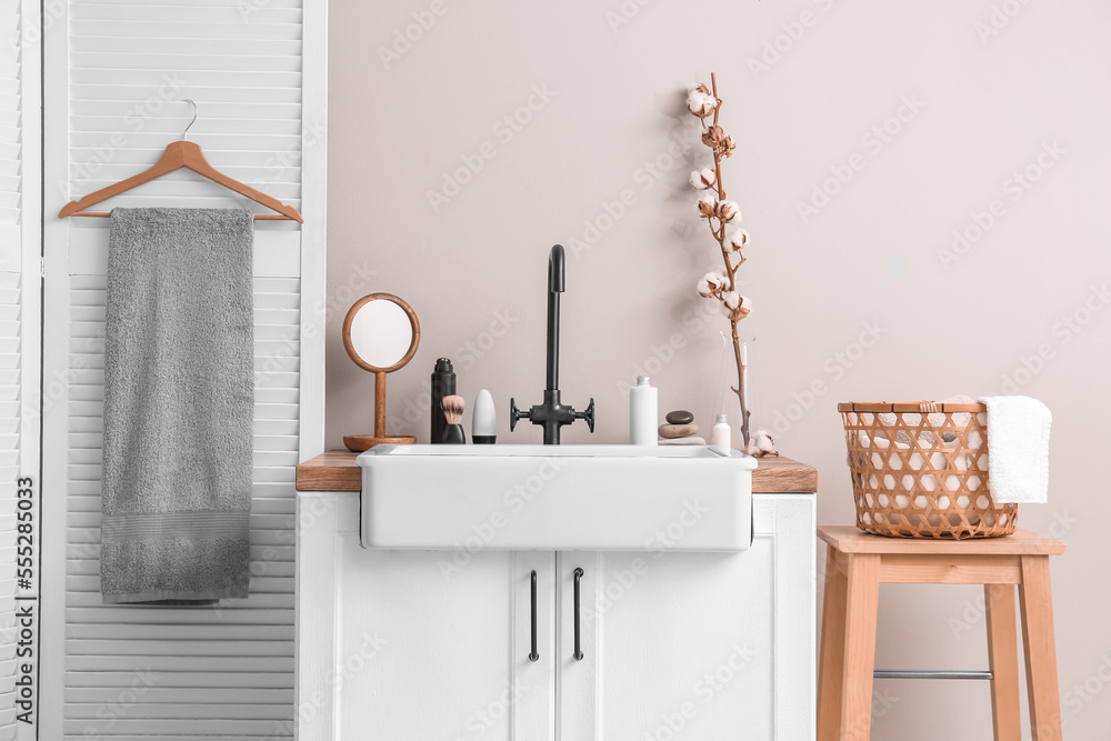 Interior of light bathroom with sink, accessories and cotton flowers