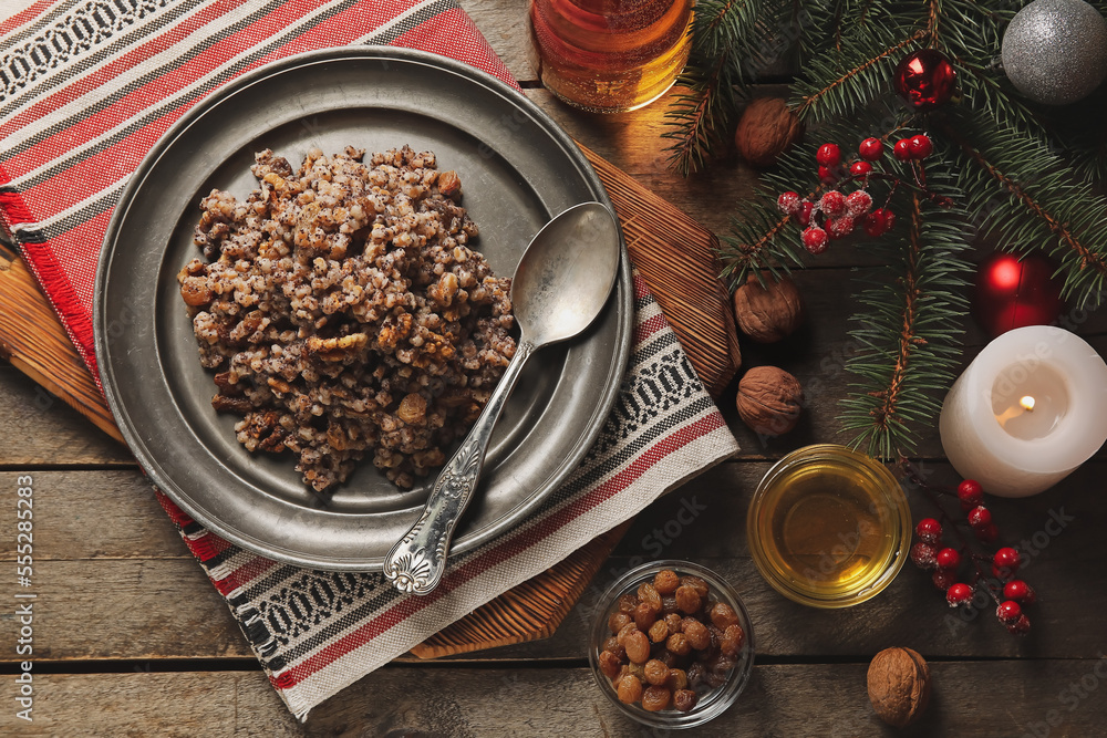 Board with plate of Kutya, ingredients and Christmas branches on wooden background