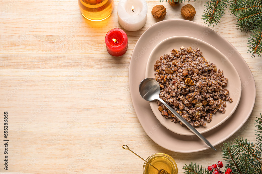 Plates of Kutya with candles and Christmas branches on wooden background