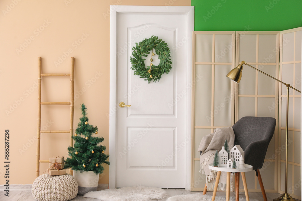 Interior of living room with door, Christmas tree and wreath