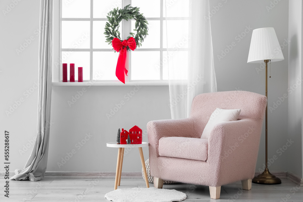 Interior of living room with Christmas wreath, armchair and table