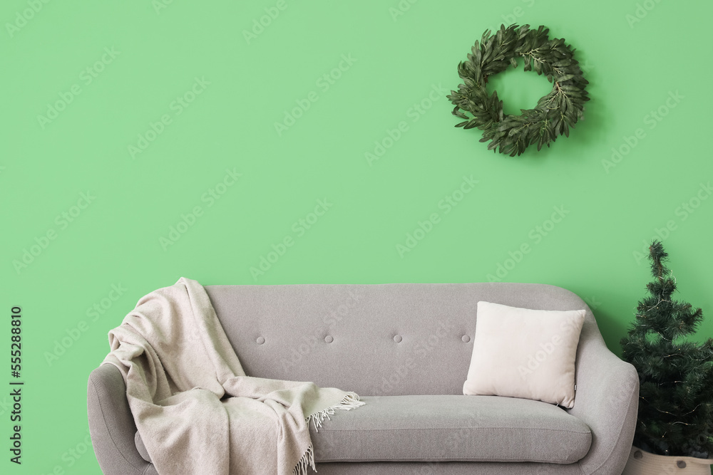 Interior of living room with Christmas wreath, fir tree and sofa