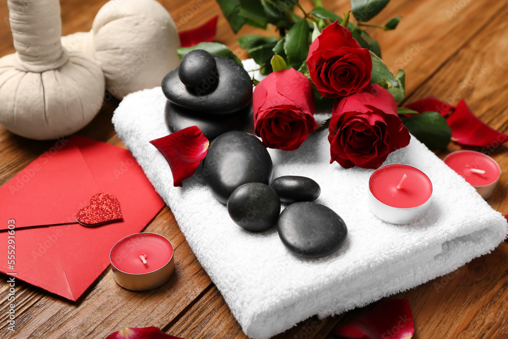 Beautiful spa composition for Valentines Day with rose flowers, stones, towel and candles on wooden