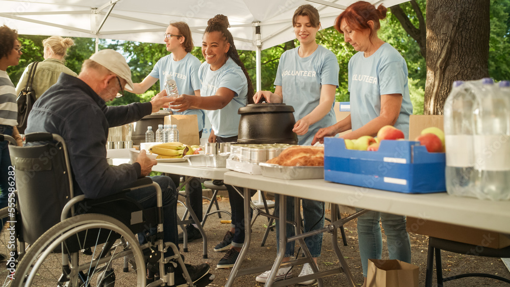 Happy Middle Aged Man with Disabilities Using Wheelchair Receiving a Charity Meal from a Humanitaria