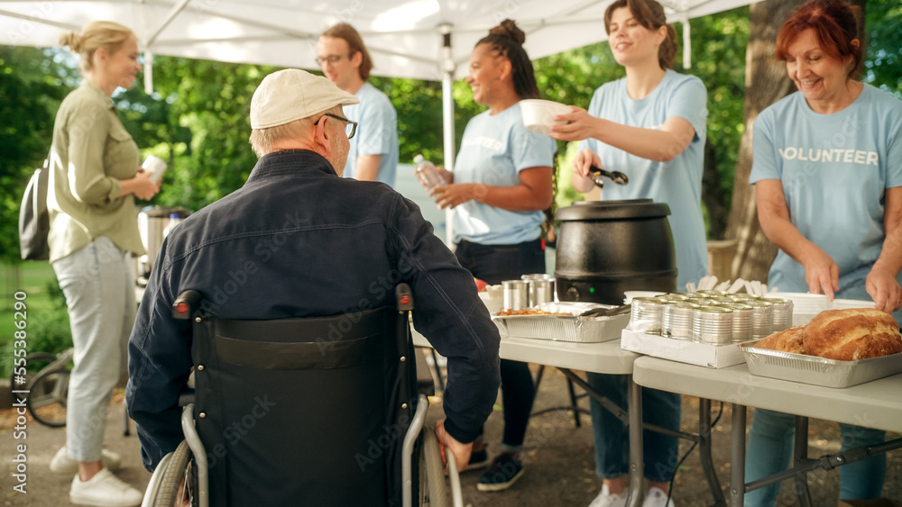 Positive and Smiling Middle Aged Man with Disabilities in a Wheelchair Receiving a Charity Meal from