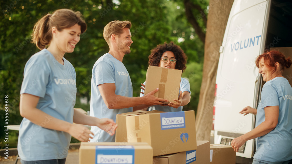 Happy Team of Young Volunteers Preparing Humanitarian Aid Rations, Food, Donations and Loading Cardb