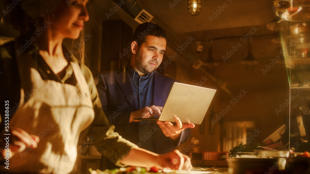 In Restaurant Small Business Owners: Male and Female Business Partners Use Laptop Computer. Authenti