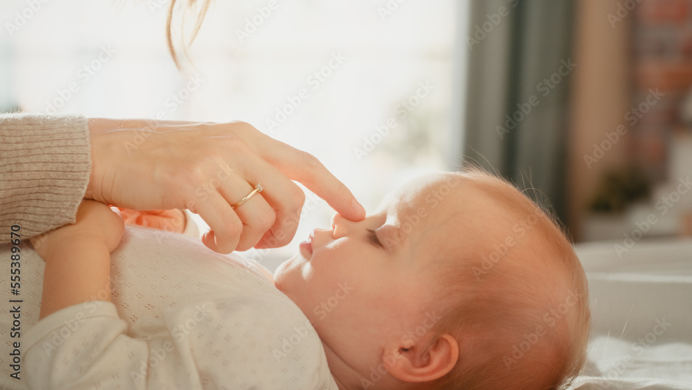 Close Up Portrait of a Loving Young Beautiful Mother Playing and Soothing Adorable Baby in Bed. Smil