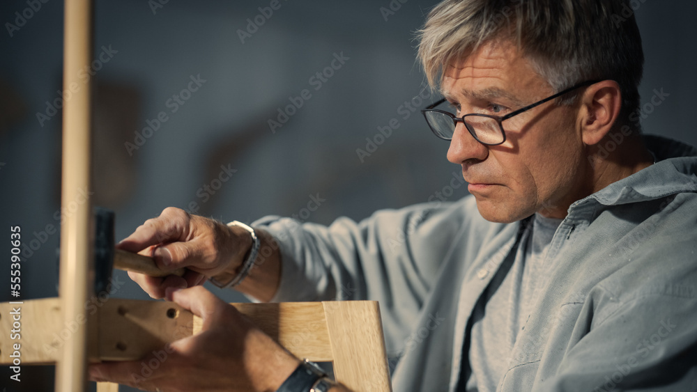 Adult Carpenter Putting on Glasses, Reading Blueprint and Starting to Assemble Parts of a Wooden Cha