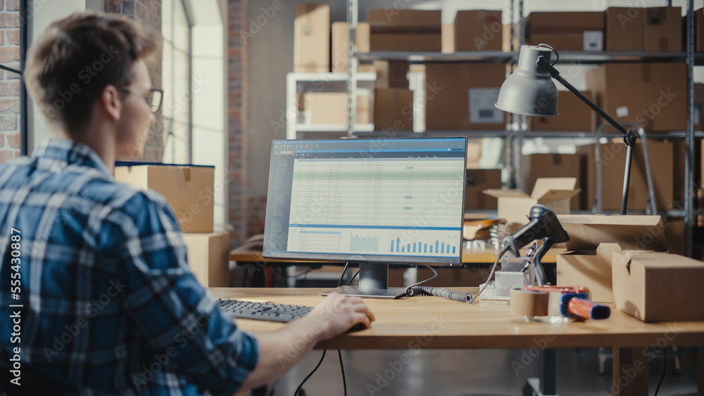 Small Business Owner Working at a Desk with Desktop Computer, Checking a Parcel Before Sending It Aw