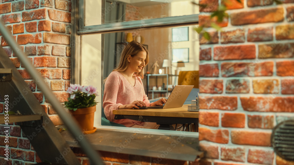 Portrait of a Young Female Student Using Laptop Computer while Sitting Behind a Table in Her Stylish