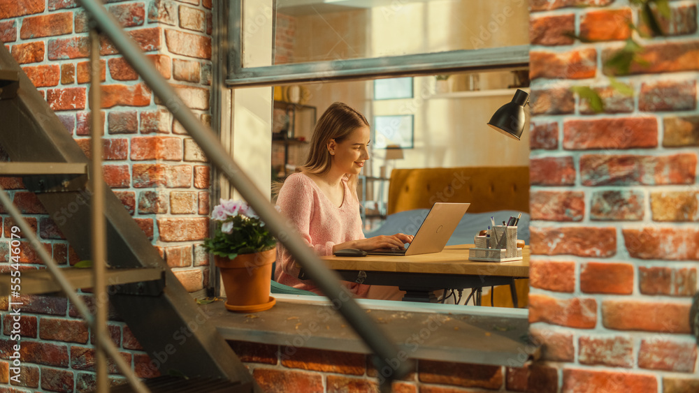 Portrait of a Female Using Laptop Computer while Sitting Behind a Table in Her Stylish Living Room. 