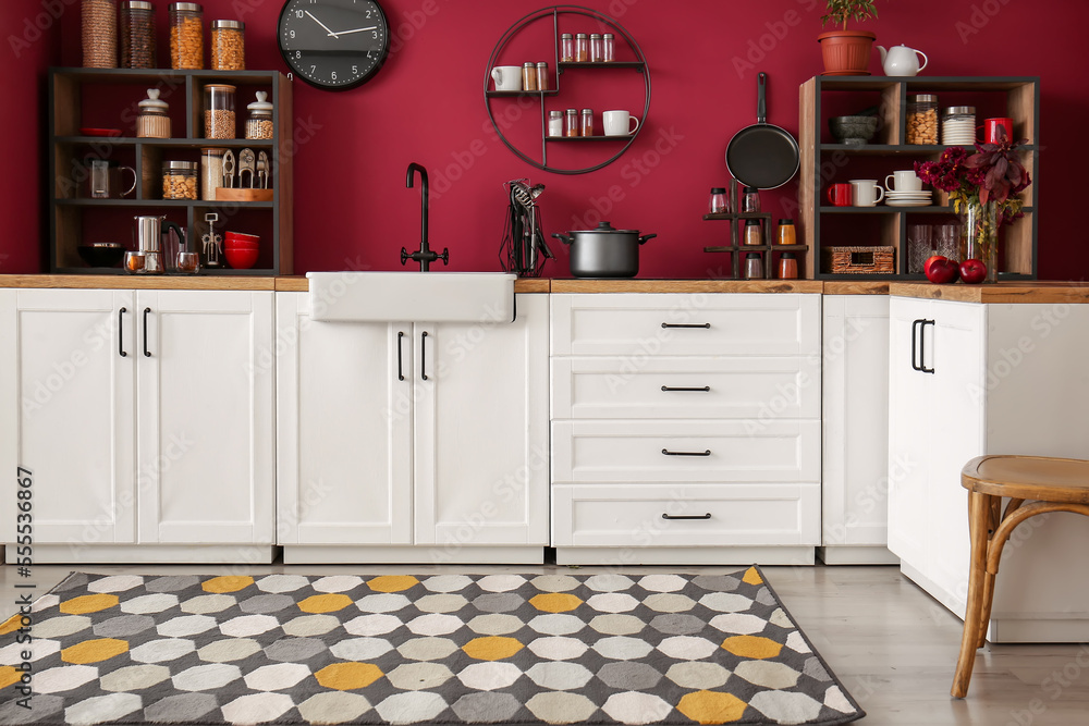 Interior of modern kitchen with stylish utensils and jars with food near color wall