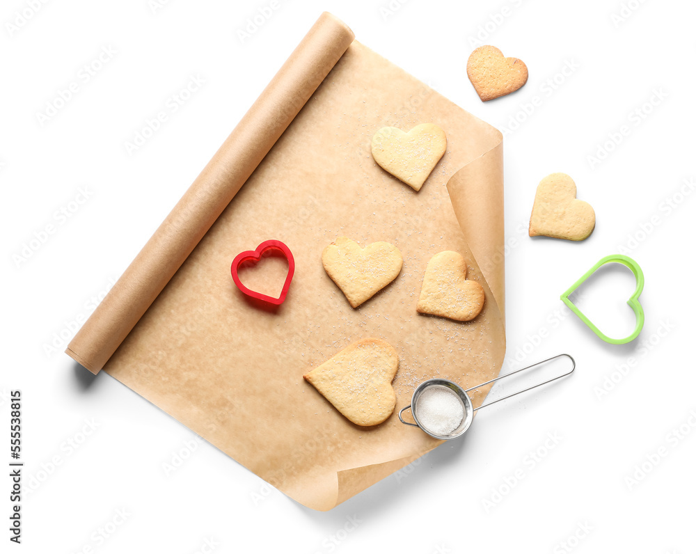 Roll of baking paper, cookies and cutters on white background