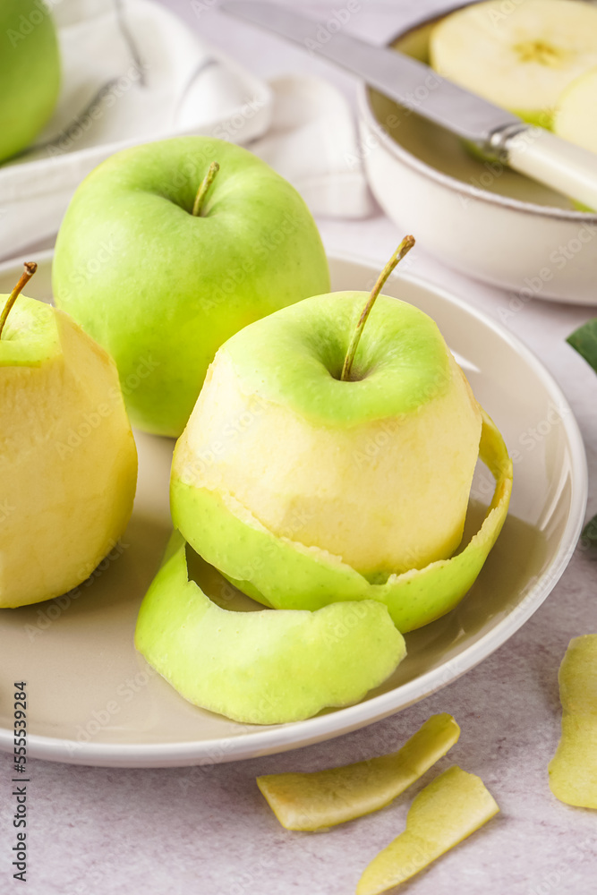 Plate with fresh juicy apples and peel on light table, closeup