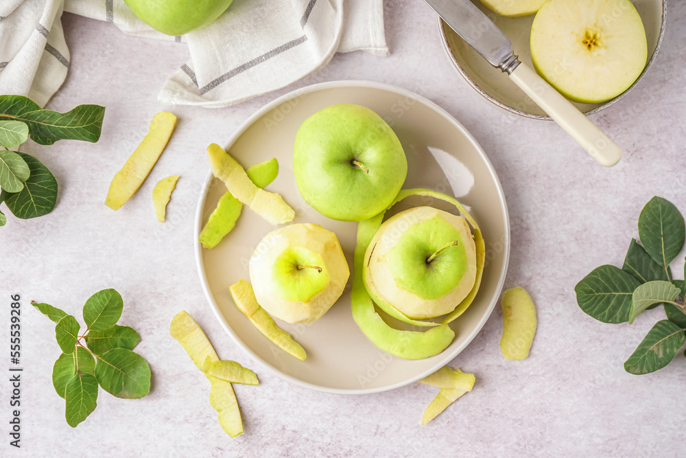 Plate with fresh juicy apples and peel on light table