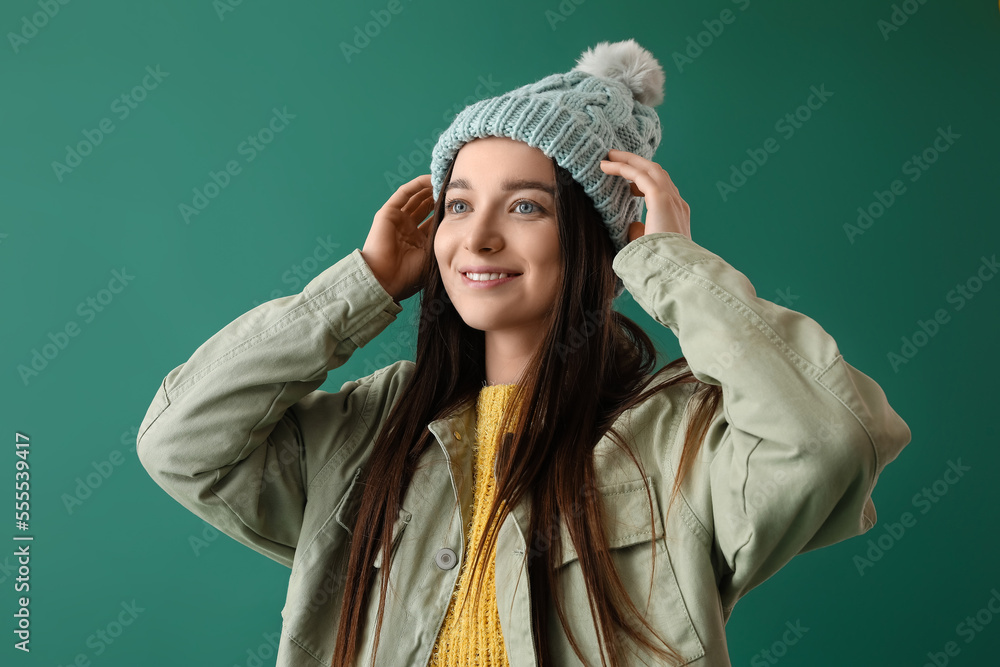 Young woman in warm hat on green background