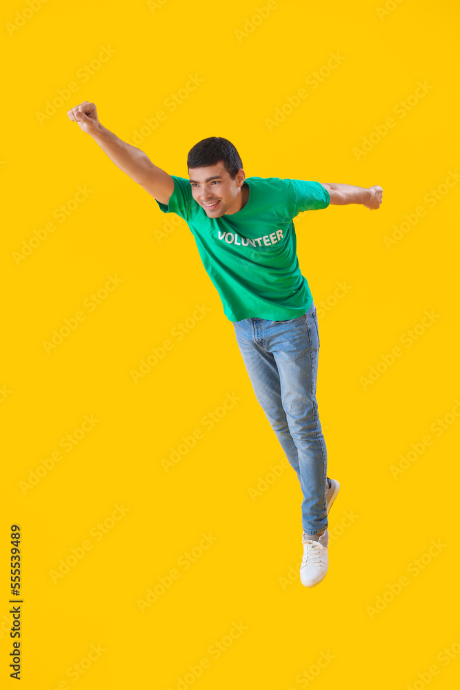 Young volunteer jumping on yellow background