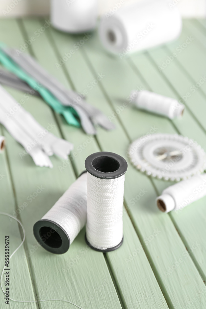 White thread spools on color wooden background