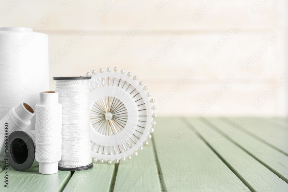 White thread spools and ball pins on color wooden table