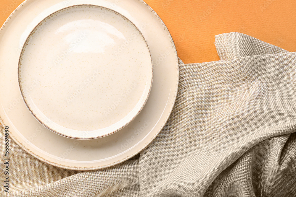 White plates and napkin on orange background